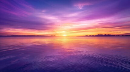 Obraz premium Brilliant purple, orange, and yellow gradients in the sky form a stunning backdrop over the calm waters of the sea at sunset.