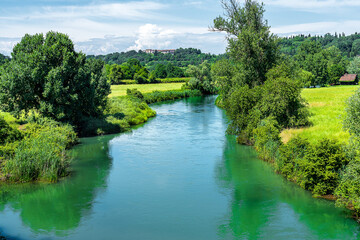 Fototapeta premium sunny midday on the shimmering colourful waters of one of the many canals of Borghetto sul Mincio Verona, a picturesque tourist village near Lake Garda