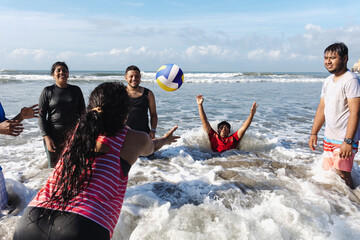 Happy latin group of friends playing volleyball at pacific ocean in Acapulco Mexico Latin America,...
