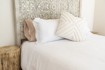 close-up of boho modern bed, hand carved wood headboard, and pillows