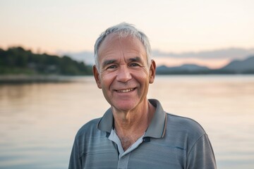 Fototapeta premium Portrait of a grinning man in his 60s wearing a sporty polo shirt on serene lakeside view
