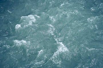 The texture of blue water, the surface of the water is blue with ripples and bubbles. A flat surface, with space for copying. High quality photo