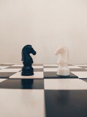 two knights of the chess facing each other on a chess board. © Saatvik