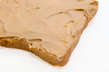 Piece of bread with peanut butter on a white background Macro
