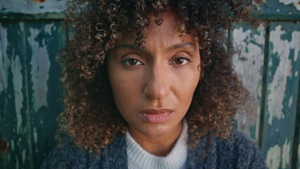 Sad woman posing door at windy day portrait. Curly tanned woman looking camera
