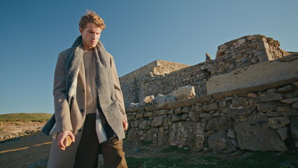 Angry man walking castle ruins place closeup. Nervous young man throwing stone
