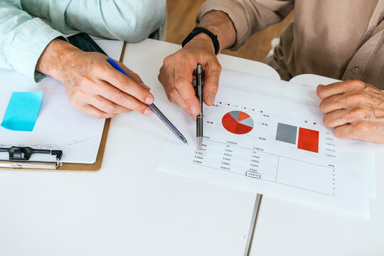 Anonymous colleagues analyzing financial charts at a desk