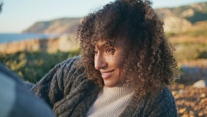 Relaxed brunette lying cliff nature smiling closeup. Happy curly woman flirting