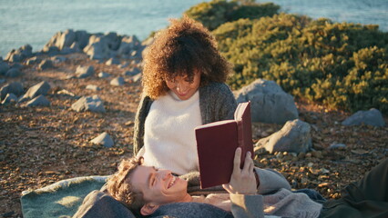 Handsome man reading book at picnic for relaxed woman closeup. Romantic couple
