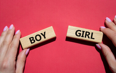 Boy or Girl symbol. Concept word Boy or Girl on wooden blocks. Man hand. Beautiful red background. Gender and Boy or Girl concept. Copy space