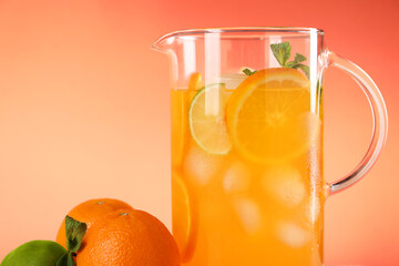 Freshly made lemonade in jug and citrus fruits against coral background