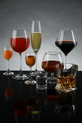 Glasses with different alcoholic drinks on table against gray background