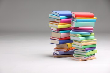 Stacks of colorful books on light grey background, space for text