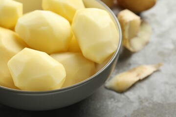 Fresh raw potatoes in bowl on grey table, closeup