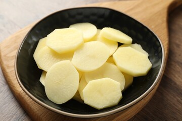 Cut fresh raw potatoes in bowl on wooden table