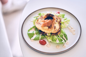 Potato pancakes with salted salmon, herbs and cream cheese sauce top view. Delicious vegetable pancakes with salmon on a plate with space to copy. High quality photo