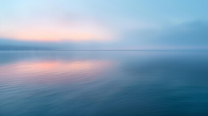 Obraz premium A quiet, foggy bay at sunrise, with calm waters reflecting the pastel colors of the morning sky.