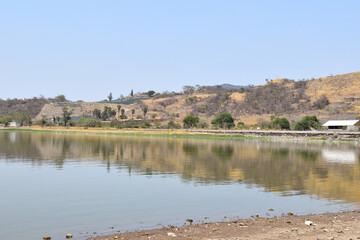 View of Valencia dam with a small town in the background. The water is still and the sky is clear, Jalisco Mexico