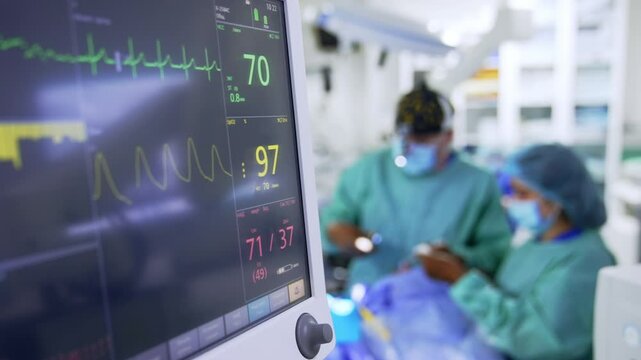 Pulse and heart rate parameters on the monitors of lung ventilating machine. Close up. Medics work at backdrop in blur.
