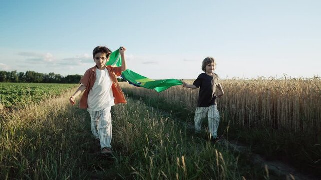 Brazilian little kids - football patriot children runs with national flag on nature background at summer sunset. Brazil celebration banner, holidays in America