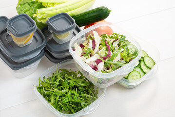 Chopped salad, vegetables and herbs in a plastic container. Storing food for freezing