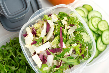 Chopped lettuce and herbs in a plastic container