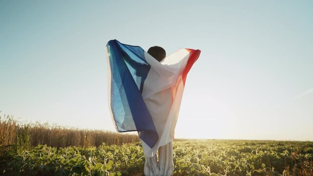 Little boy - French patriot kid jumping with national flag on open area at sunset. Celebration. Banner, election, France, labor