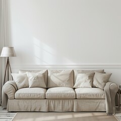 A beige couch sits in front of a blank white wall in a simple living room. A lamp is nearby.