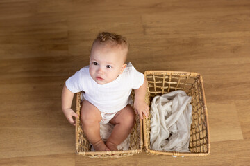 boy in white sitting in a basket on the floor