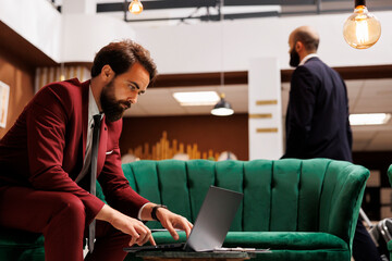 White collar worker check documents to kill time before starting meeting, sit in lounge area. Entrepreneur preparing notes for executive board presentation, luxury lobby at hotel.