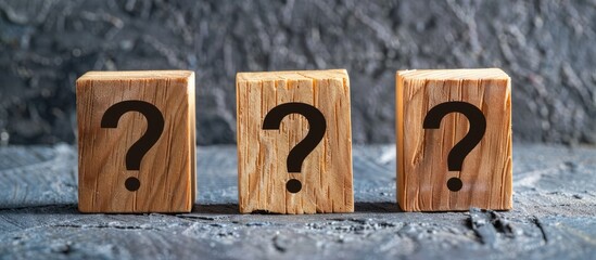 Question mark printed on three wooden blocks, placed on a dark backdrop