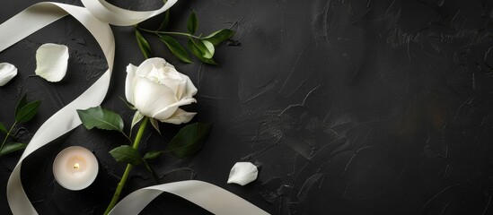 Funeral-themed photo display featuring ribbon, white rose, and candle on dark surface with black backdrop. Design space available