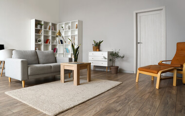 Interior of light living room with grey couch, table and shelving unit