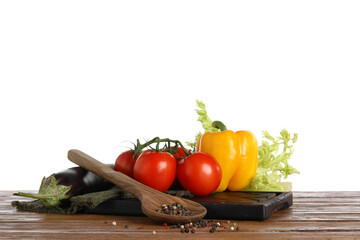 Board with fresh vegetables and spoon on brown wooden kitchen table against white background