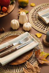 Stylish table setting with candles and autumn decor on brown background
