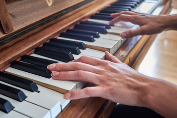 Young woman's hands playing on an old piano, close-up