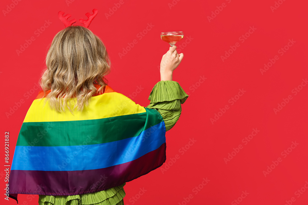 Sticker beautiful young woman in reindeer horns with lgbt flag and glass of champagne on red background. chr