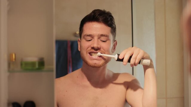 Dental, face and man brushing teeth with electric toothbrush in a bathroom for hygiene, wellness and fresh breath. Oral care, mouth and portrait of male cleaning tooth and gums with toothpaste in his