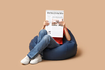 Woman in beanbag chair with newspaper on beige background