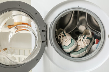 Open washing machine with sneakers, closeup