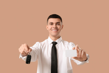 Naklejka premium Young man with blank driving license and car key on brown background