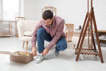 Young man trying on stylish sneakers in boutique