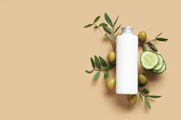 Bottle of cosmetic product with olives and cucumber on brown background