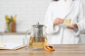 Teapot of green tea with slice of lemon on table in kitchen