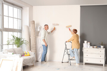 Fototapeta premium Mature couple painting wall during repair in their new house