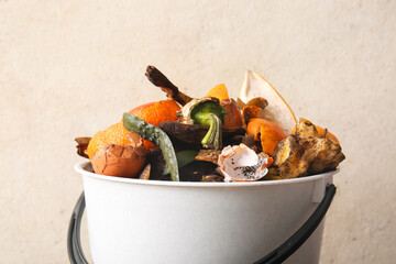 Bucket with organic waste on white grunge background, closeup. Compost recycling concept