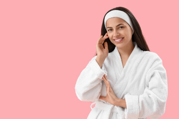 Beautiful young happy woman in bathrobe on pink background