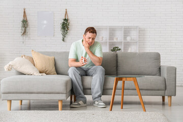 Obraz premium Young man with cup suffering from toothache in room