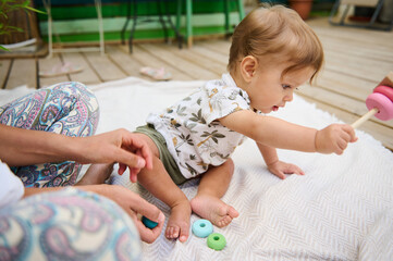 Adorable baby boy playing with wooden pyramid, playing educational and developmental games, developing motor skills and thinking. Childhood and Kids entertainment