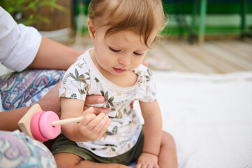 Adorable baby boy playing with a colorful wooden pyramid from eco wood, playing educational and developmental games, developing motor skills and thinking. Childhood and Kids entertainment